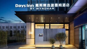 A hotel entrance with a sign for Days Inn by Wyndham, featuring a modern design with a flat roof and large windows.