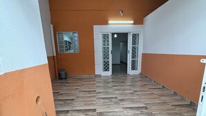 An interior corridor with a tiled floor, a door with glass panels, and a ceiling with wooden beams. - Agrishow house, sleeps 4 / 2 bedrooms / 1 bathroom (Ribeirão Preto)