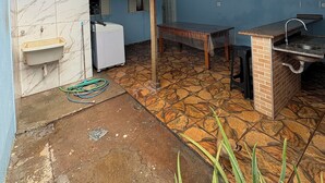 A covered outdoor area with a sink, a table, and a barbecue grill. - Agrishow house, sleeps 4 / 2 bedrooms / 1 bathroom (Ribeirão Preto)