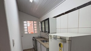 A kitchen with a refrigerator, stove, sink, and tiled backsplash. - Agrishow house, sleeps 4 / 2 bedrooms / 1 bathroom (Ribeirão Preto)