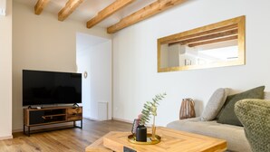 Ein Wohnzimmer mit Fernseher, Couch, Holz-Couchtisch und einem Spiegel an der Wand.