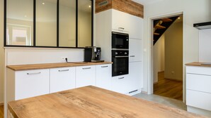 Eine moderne Küche mit weißen Schränken, einer Holzauskładung, einer eingebauten Mikrowelle und einem Backofen.