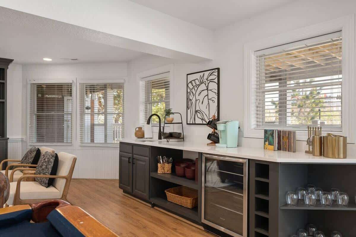 A modern kitchen with a central island, built-in cabinets, and a large window with blinds.