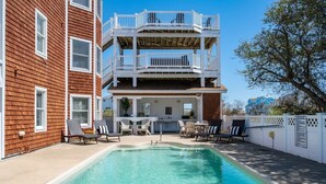 Ein zweistöckiges Gebäude mit Schwimmbad, Sitzgelegenheiten im Freien und einem Balkon.