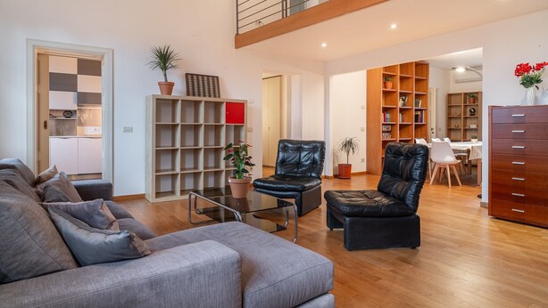 A modern living room with a sofa, leather chairs, a glass coffee table, and a bookshelf. - Chica's Luxury Loft in the Heart of Lucca's Historic Center (Lucca)