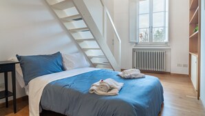A bedroom with a bed, a window, a radiator, and a staircase. - Chica's Luxury Loft in the Heart of Lucca's Historic Center (Lucca)