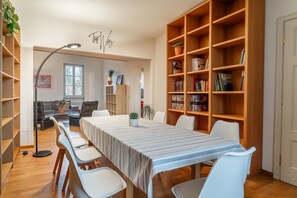 A room with a long table, white chairs, a bookshelf, and a lamp. - Chica's Luxury Loft in the Heart of Lucca's Historic Center (Lucca)