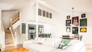 A modern living room with a wooden staircase, a white sofa, a wooden coffee table, and a dining area with chairs. - Abbey Springs Resort with Golf Cart, Shared Pools (Fontana-on-Geneva Lake)