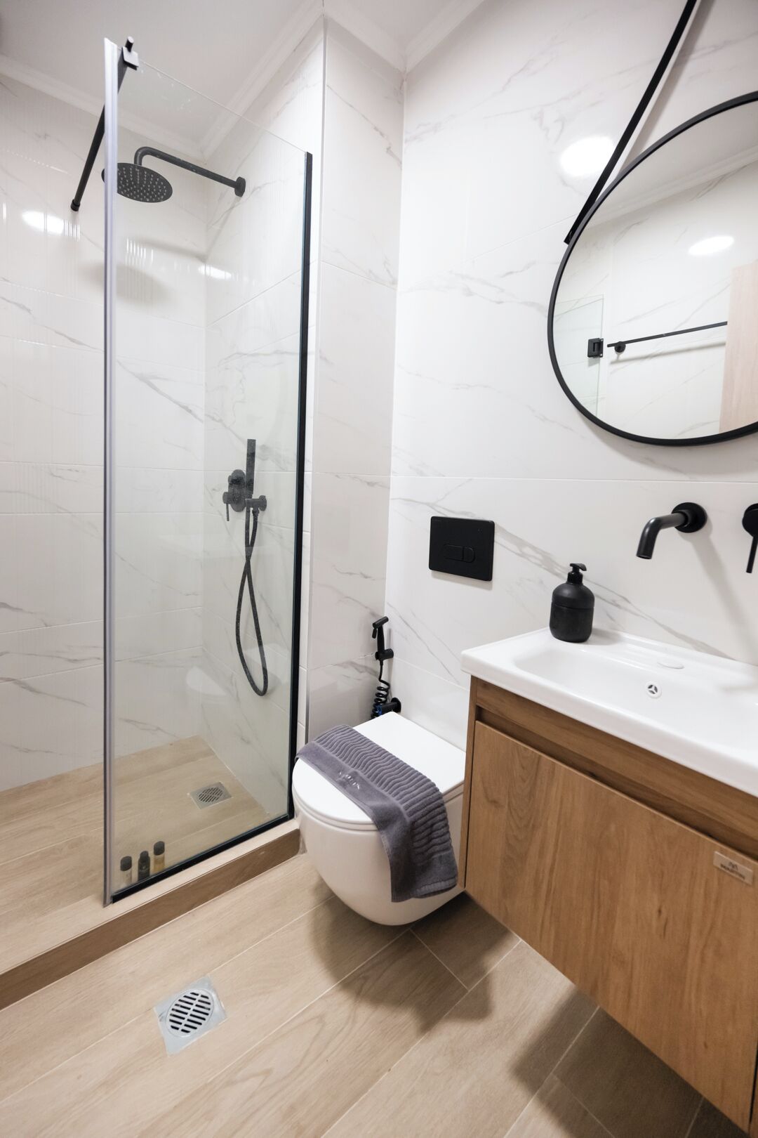 Ein modernes Badezimmer mit einer Duschkabine aus Glas, einer Toilette und einem Waschbecken mit Spiegel darüber.