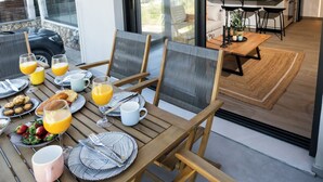 An outdoor dining area with a table set for breakfast, including plates, cups, and glasses. - Nicole Collection - Meganisi Cove Suites (Meganisi)