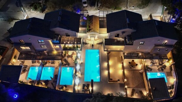 A modern hotel with a central swimming pool, multiple balconies, and outdoor seating areas. - Nicole Collection - Meganisi Cove Suites (Meganisi)