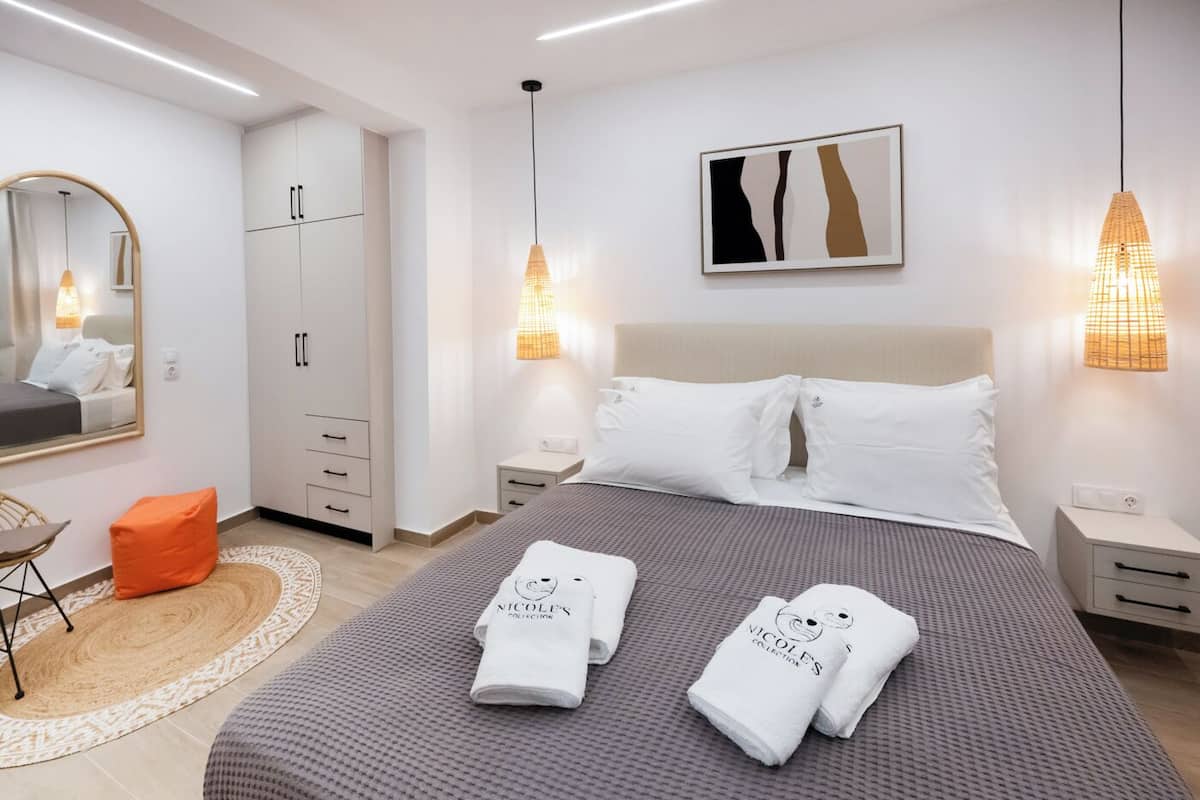Une chambre d’hôtel moderne équipée d’un grand lit, d’une armoire, d’un bureau et d’un miroir.