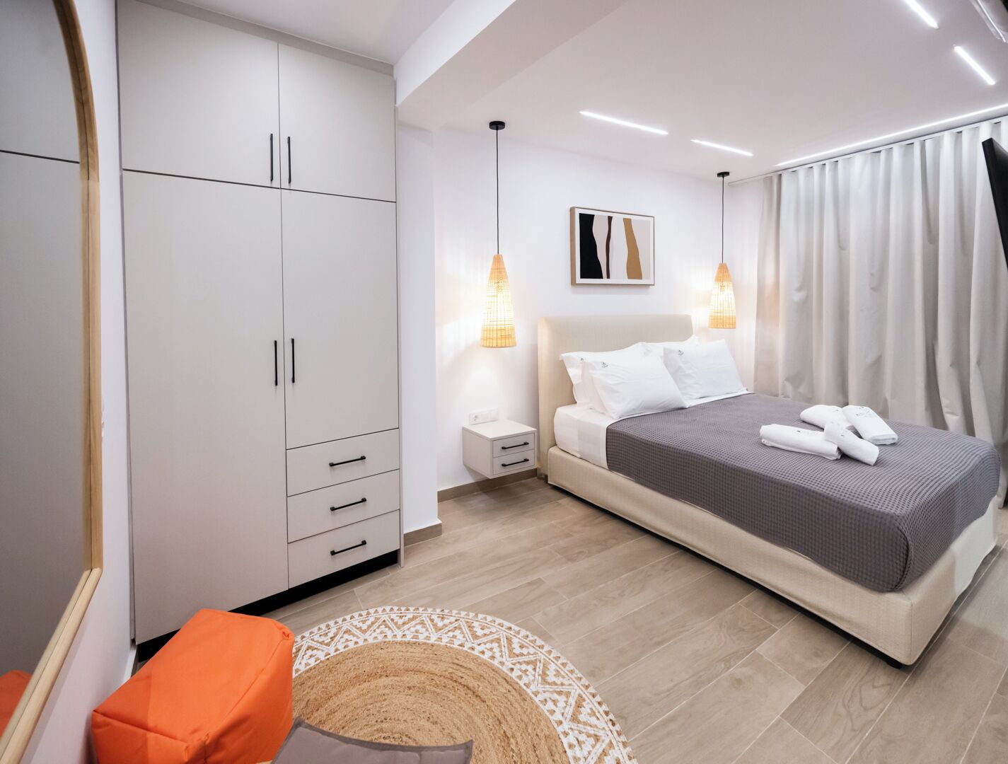 A modern bedroom with a bed, nightstand, wardrobe, and a decorative rug.