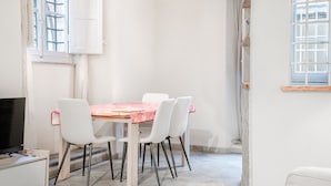 Een eetgedeelte met een tafel, stoelen, een televisie en een raam met uitzicht.
