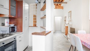 Een moderne keuken met witte kasten, een magnetron, een fornuis en een houten aanrecht.