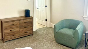 A room with a wooden dresser, a teal armchair, a white door, and a small table. - Timeless Elegance at a Historic Kentucky Inn (Versailles)