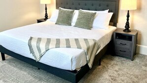A bed with a grey headboard, two bedside tables with lamps, and a striped throw blanket. - Timeless Elegance at a Historic Kentucky Inn (Versailles)
