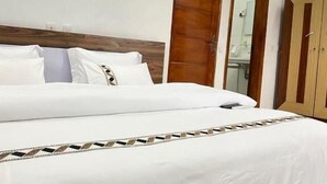Une chambre d’hôtel avec un grand lit, une armoire en bois et un miroir.
