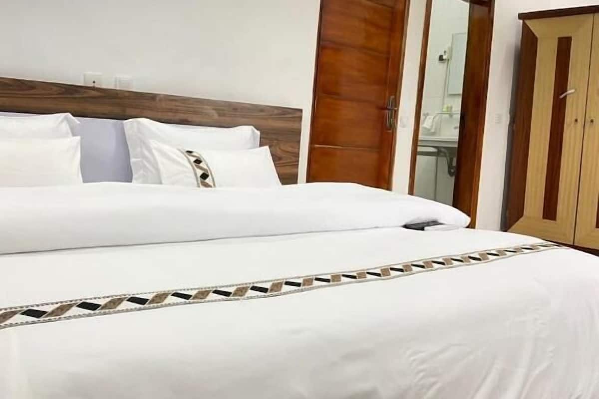 Ein Hotelzimmer mit einem großen Bett, einem Holzschrank und einem Spiegel.