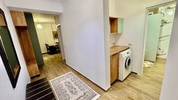 A modern apartment with a staircase, a washing machine, and a dining area.