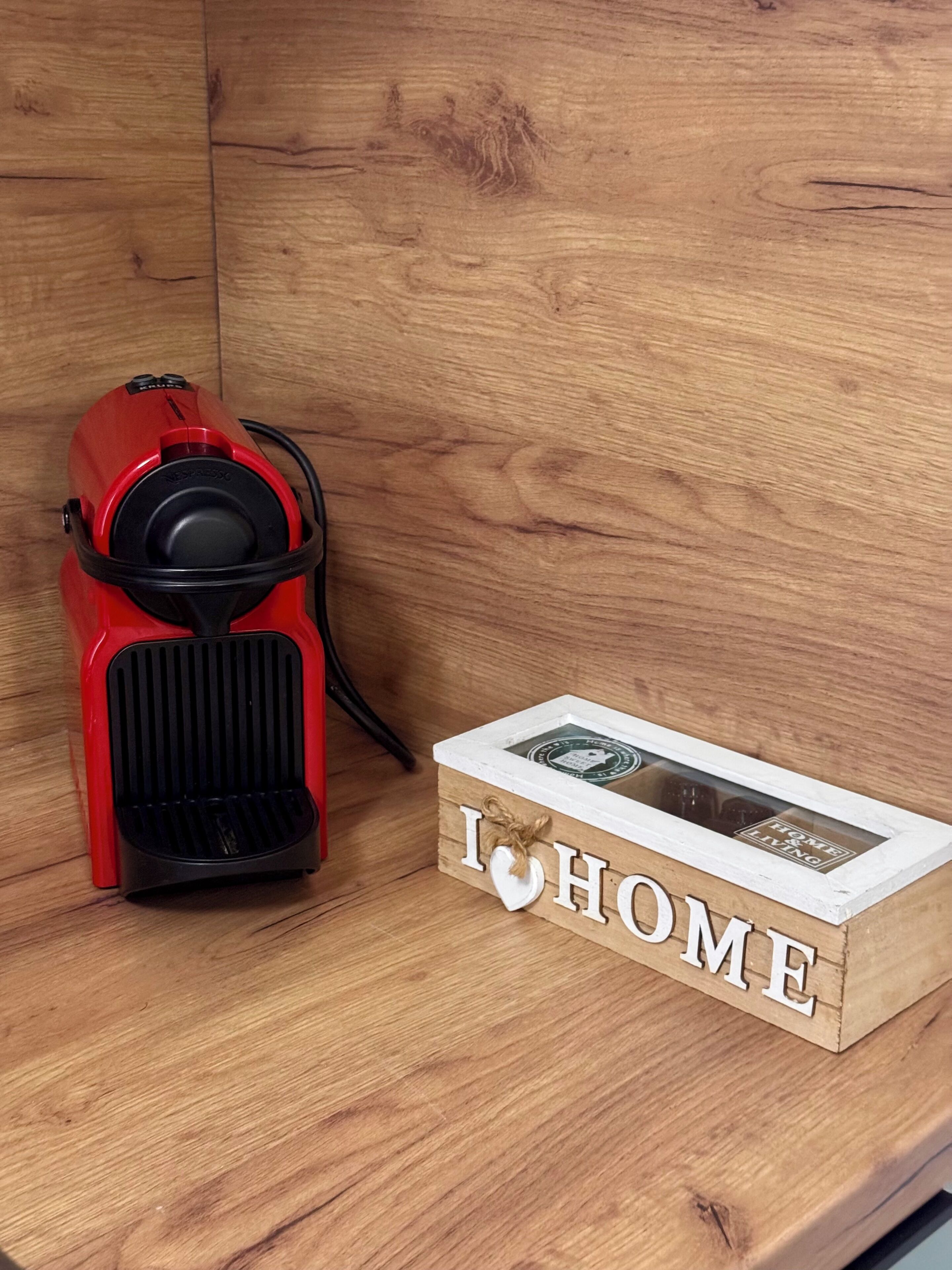 A red espresso machine next to a wooden box with 'I ♥ HOME' written on it.