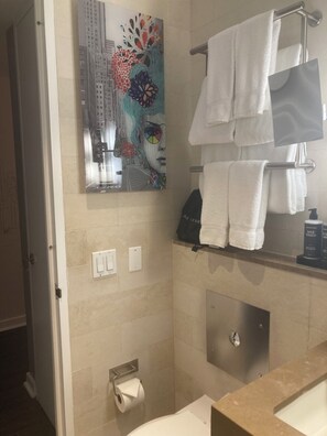 Ein Badezimmer mit Dusche, Toilettenpapierhalter, Handtuchhalter und mehreren Handtüchern sowie einer Wanddekoration.