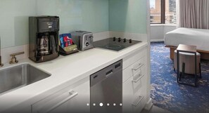 Eine kleine Küchenzeile im Hotel mit Kaffeemaschine, Toaster und einem Geschirrgestell.