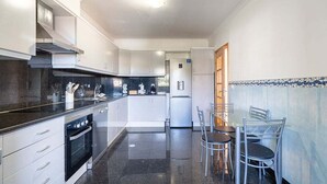 Une cuisine moderne avec des meubles blancs, un plan de travail noir et un coin repas comprenant une table et des chaises.