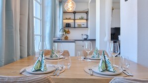 A dining table set with plates, cutlery, and napkins, with a kitchen in the background.