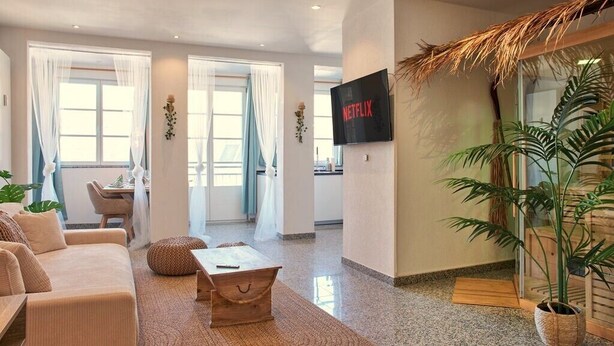 A modern living room with a sofa, coffee table, and a TV displaying 'NETFLIX'.