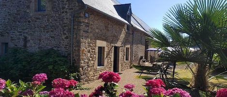 A stone building with a sloped roof, a small window, and a door.