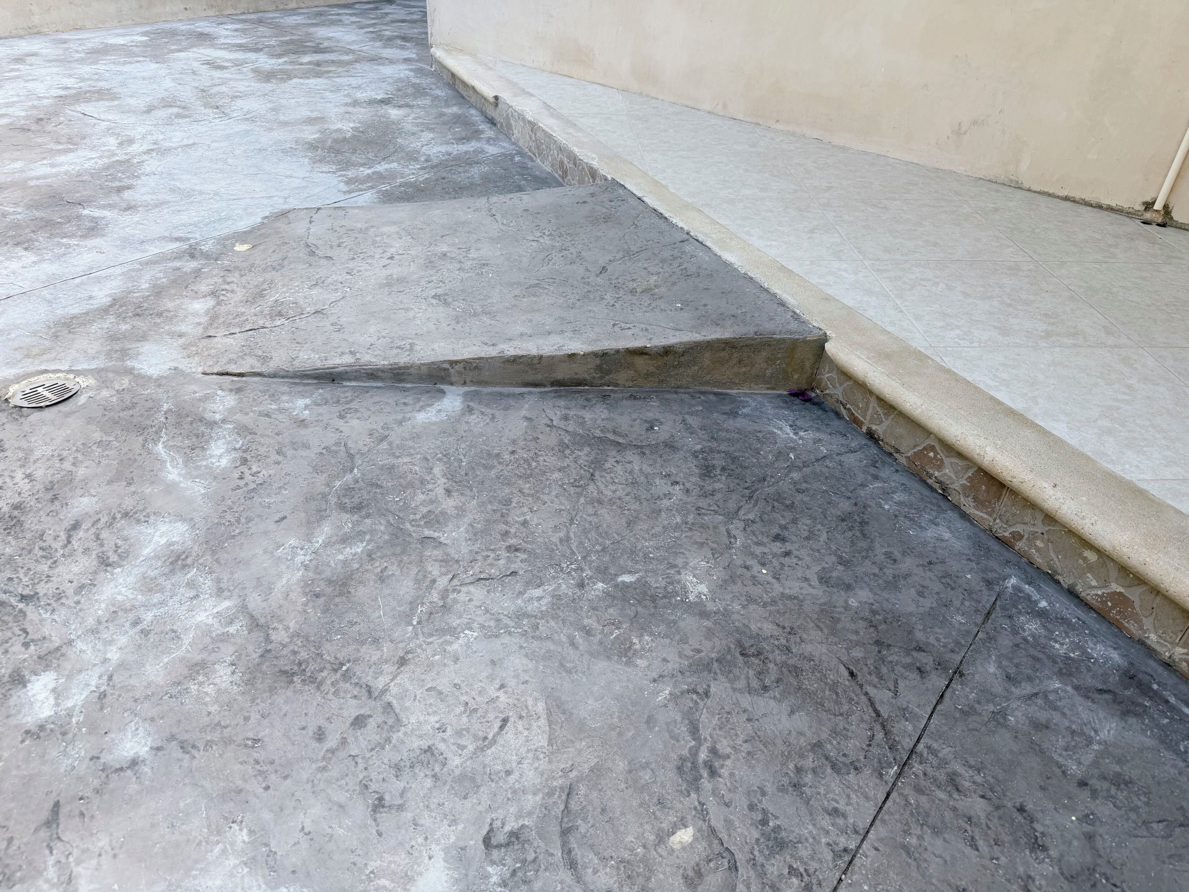 A concrete floor with a visible crack and a drain cover.