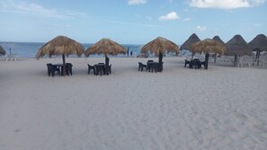 Ein Strand mit Reetdachschirmen und Plastikstühlen.