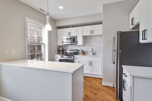 A modern kitchen with white cabinetry, stainless steel appliances, and a central island. - MTR~TopFloor~Patio~PetFriendly~FreeParking (Chicago)