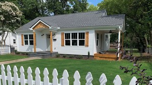 A single-story house with a porch, a front yard, and a white picket fence. - Cute & Cozy 2 Bdrm Getaway  Close to Downtown (Greer)