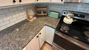 A kitchen with white cabinets, a toaster, a kettle, and a stove. - Cute & Cozy 2 Bdrm Getaway  Close to Downtown (Greer)