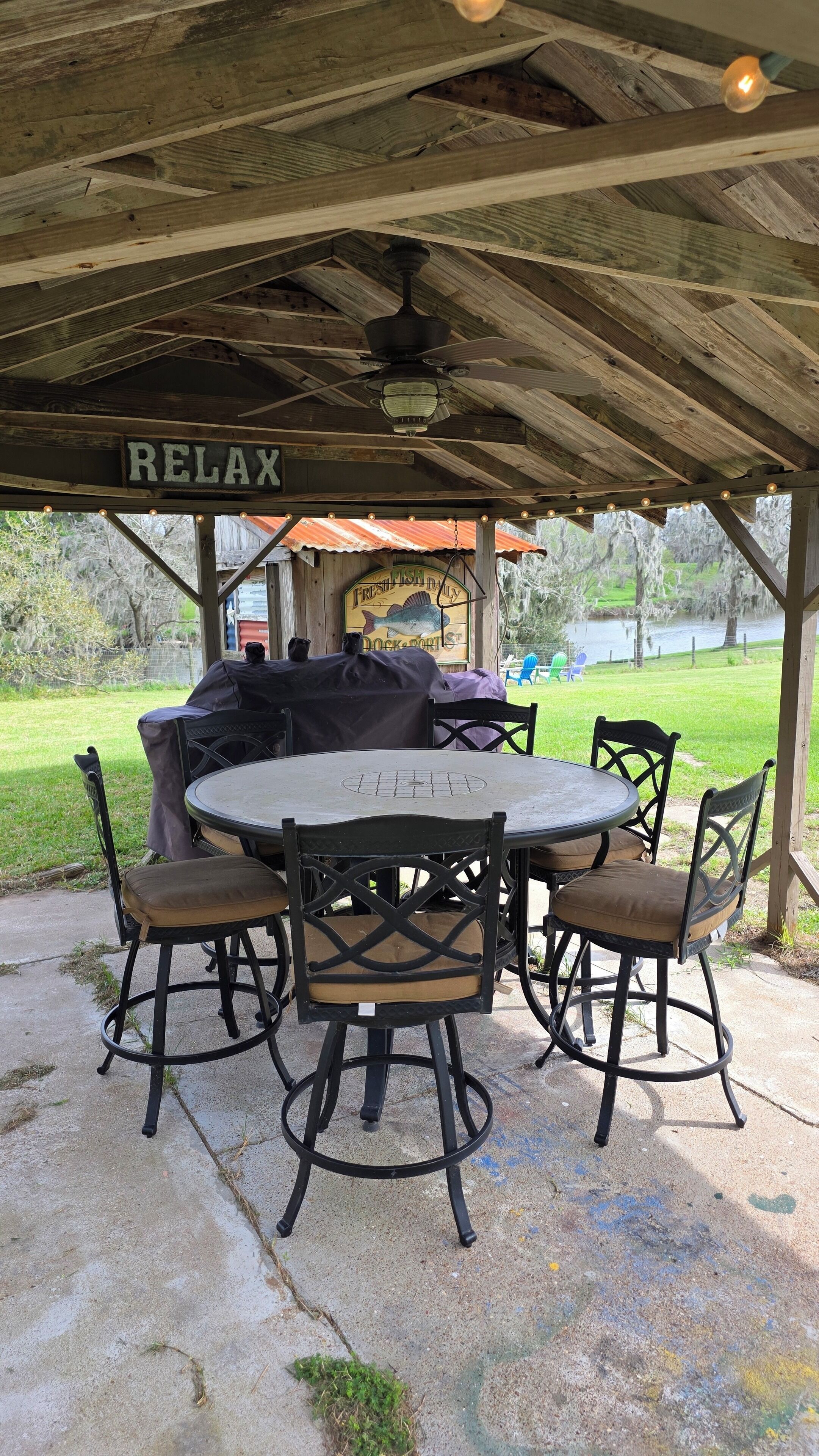An outdoor patio with a table and chairs, a ceiling fan, and a sign that reads 'RELAX'.