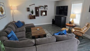 A living room with a sectional sofa, a coffee table, a TV, and a leather chair.