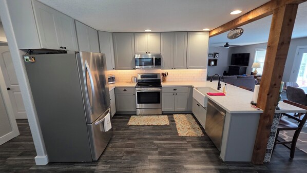A modern kitchen with grey cabinets, stainless steel appliances, a microwave, and a built-in oven.