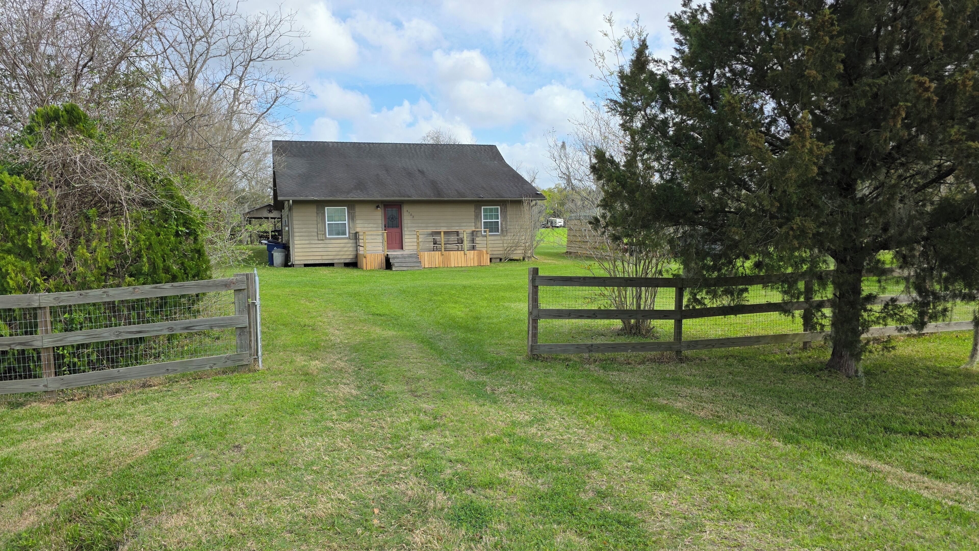 A house with a front yard, a wooden fence, and a clear sky.