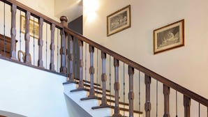 A staircase with wooden balusters, a hanging light fixture, and framed pictures on the wall. - Villa nestled in the vineyards of chianti with private pool (Pieve A Presciano)