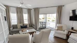 Ein modernes Wohnzimmer mit einer Couch, zwei Sesseln, einem Couchtisch und einem an der Wand befestigten Fernseher.