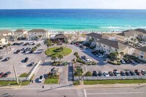 A coastal hotel with multiple parking lots, a central landscaped area, and ocean views. - Beachwalk Bliss at Sandpiper Cove Unit 9216 – Gulf Views & Steps to the Beach! (Destin)