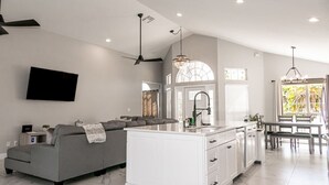 A modern kitchen with white cabinetry, a central island, and a dining area with a table and chairs. - Pool, Park, & Ramp! Book today! (Port St. Lucie)