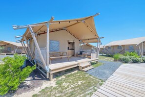 A series of wooden cabins with attached verandas, a picnic table, and a small garden area. - Chincoteague Bay RV Resort & Cottages (Chincoteague)