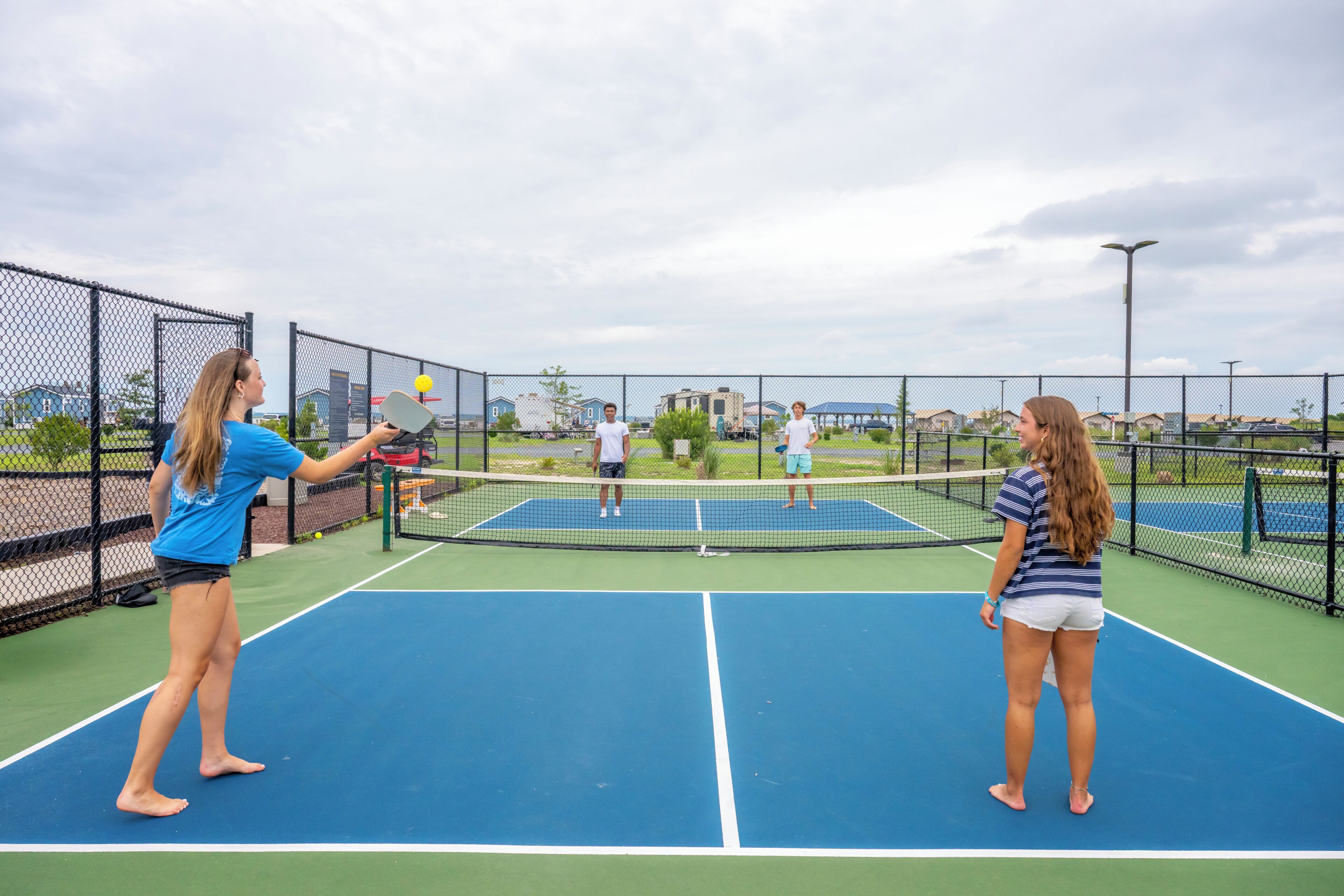Een buiten tennisbaan met een net, omringd door een hek van gaas.