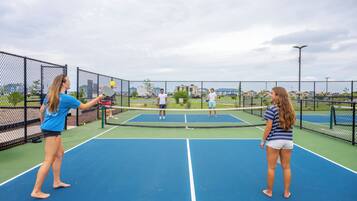 Een buiten tennisbaan met een net, omringd door een hek van gaas.