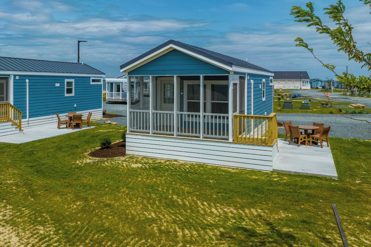 A row of blue mobile homes with porches and outdoor seating.