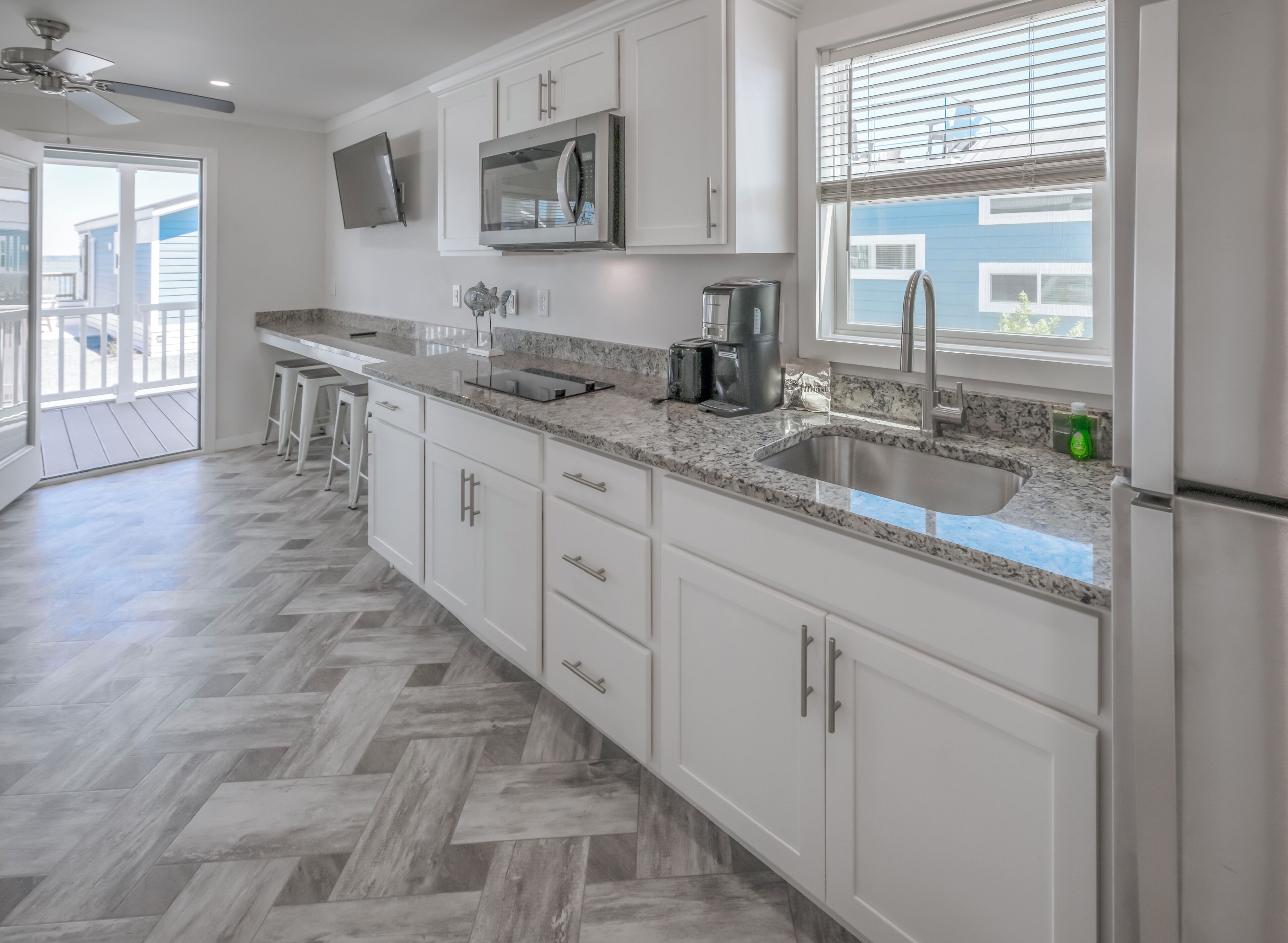 A modern kitchen with white cabinets, a granite countertop, a stainless steel sink, and a built-in microwave.