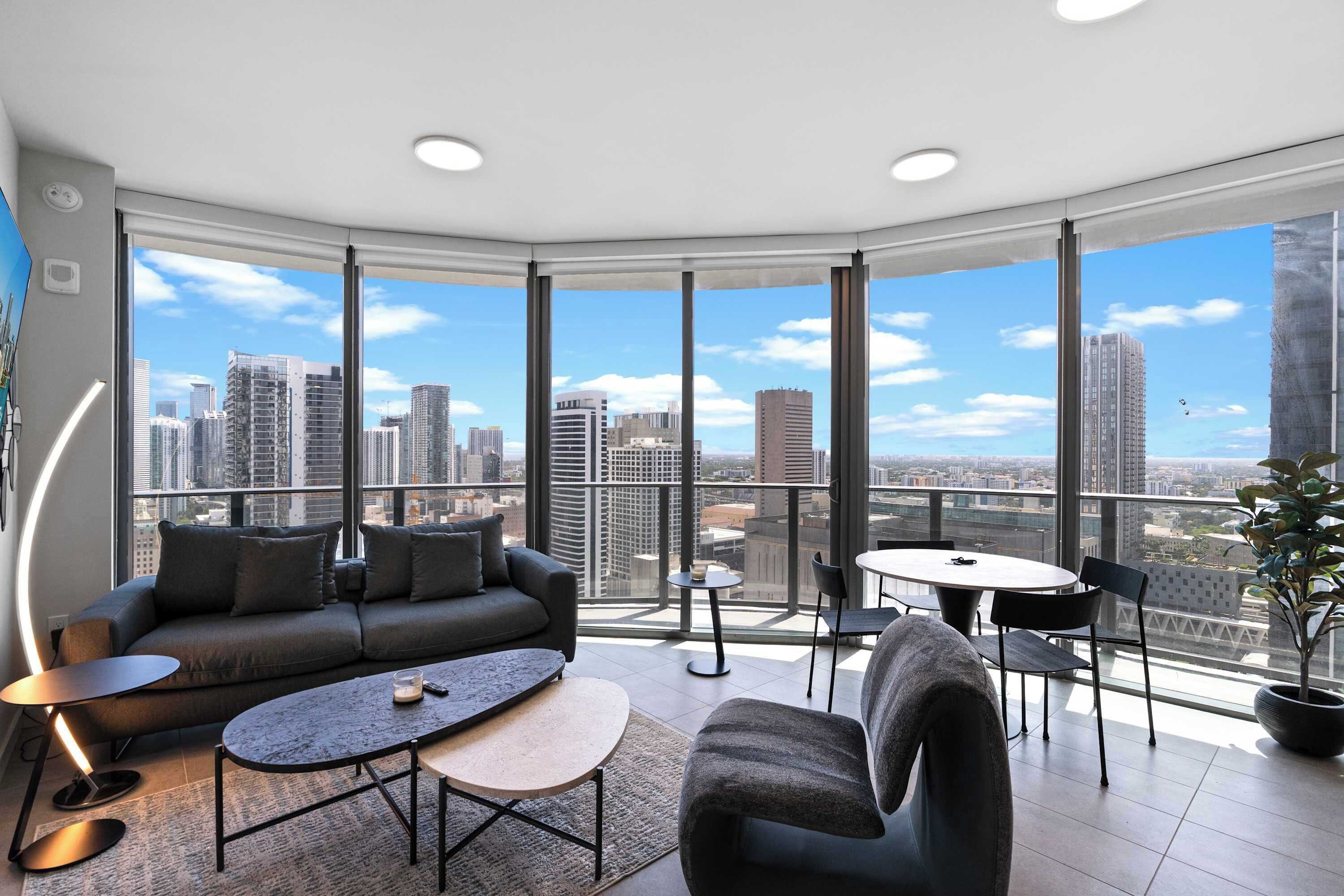 Un salon moderne avec vue sur la ville, comprenant un canapé, une table basse et un coin repas.